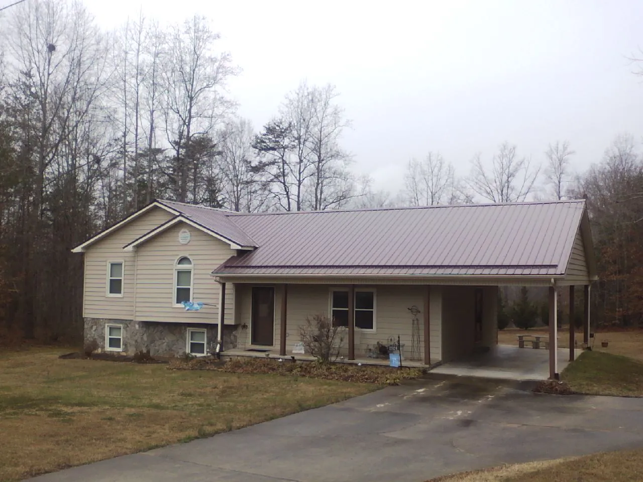 Burgundy metal roof on a tan split level home with an attached carport in Edgerton